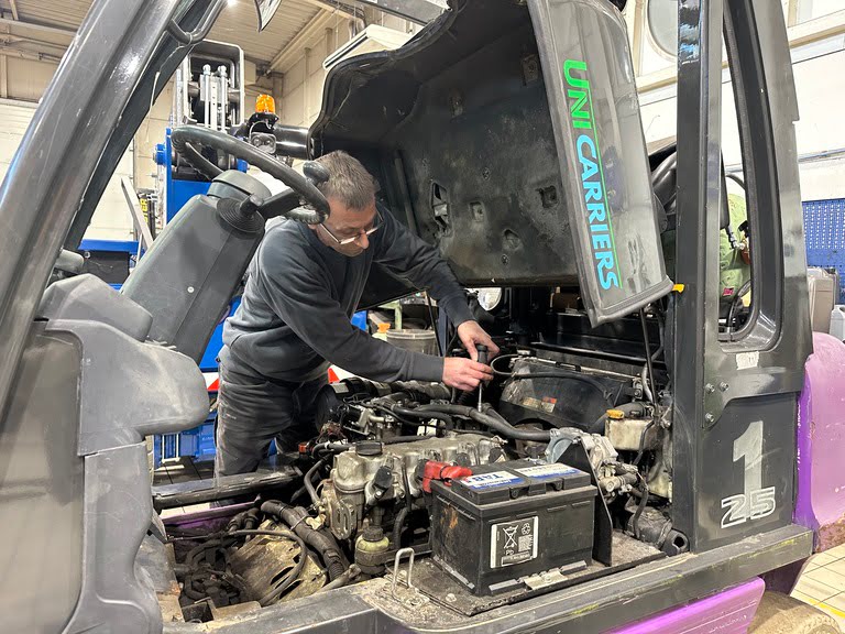 Photo d'un technicien dans un atelier en train de réparer le moteur d'un chariot élévateur unicarriers