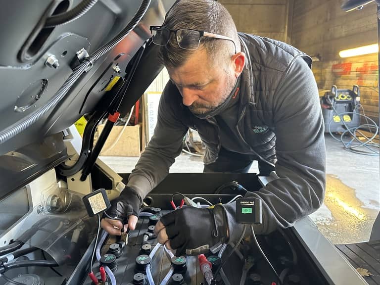 Photo d'un technicien en cours de réalisation d'une régénération de batterie sur un chariot élévateur