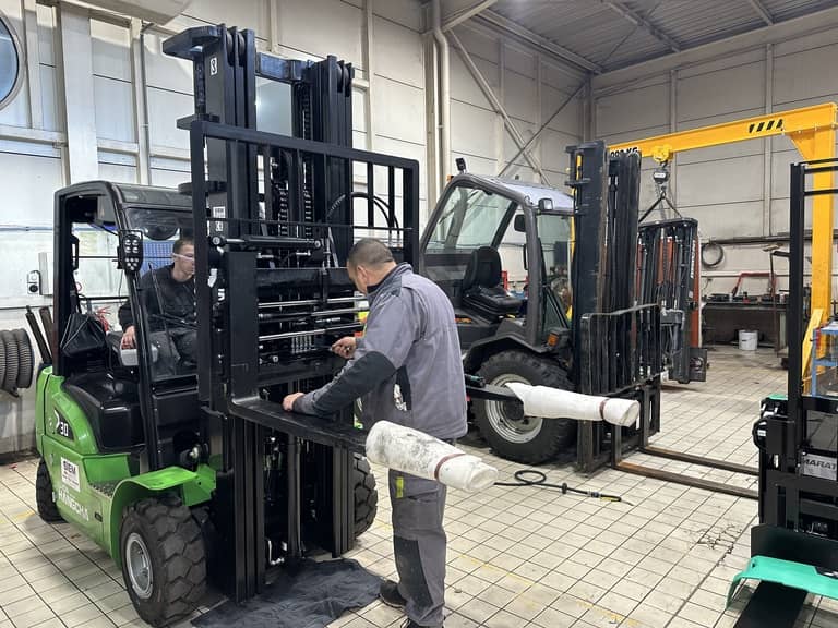 Photo d'un technicien atelier en cours d'installation d'un accessoire de manutention sur un chariot élévateur frontal Hangcha lithium