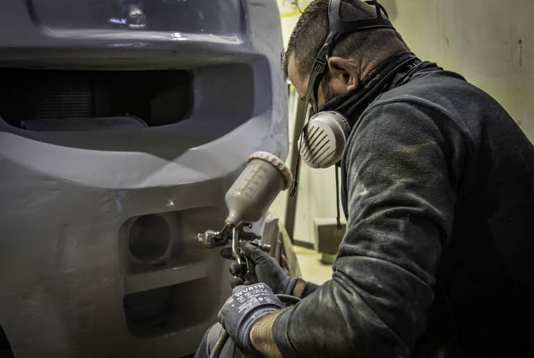 Photo d'un technicien atelier en train de réaliser une remise en peinture sur un chariot élévateur