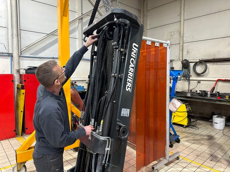 Image d'un technicien en train de remplacer un flexible hydraulique sur le mât d'un chariot élévateur