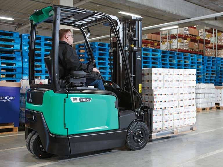 Photographie d'un cariste aux commandes d'un Chariot élévateur FB14N2T de Mitsubishi Forklift, transportant une palette chargée