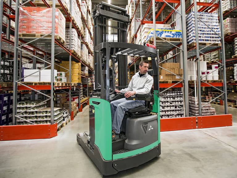 Image d'un cariste à l'intérieur d'un chariot à mat rétractable RB16-25N3 de Mitsubishi Forklift, circulant dans un espace de stockage