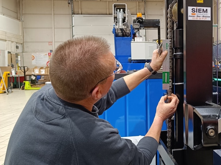 Un technicien de Siem Services assure la maintenance d'une chaîne sur un gerbeur Mitsubishi Forklift