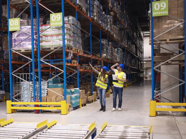 2 salariés en gilet de sécurité réalisent un diagnostic dans un entrepôt logistique